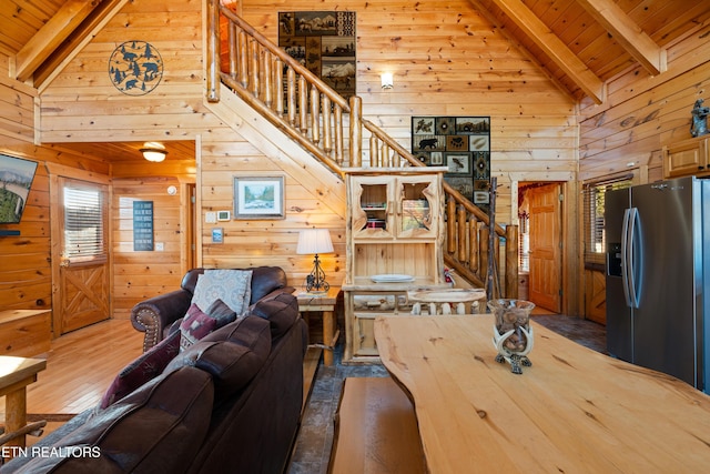 living room featuring beam ceiling, high vaulted ceiling, wooden ceiling, and wooden walls