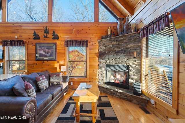 living room featuring high vaulted ceiling, wooden walls, beamed ceiling, a fireplace, and hardwood / wood-style floors