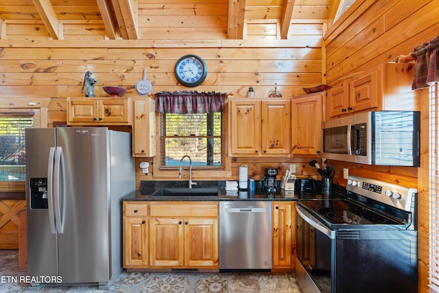 kitchen featuring sink, beam ceiling, wooden walls, and appliances with stainless steel finishes