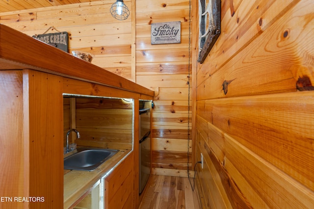 bathroom featuring sink, hardwood / wood-style floors, and wood walls