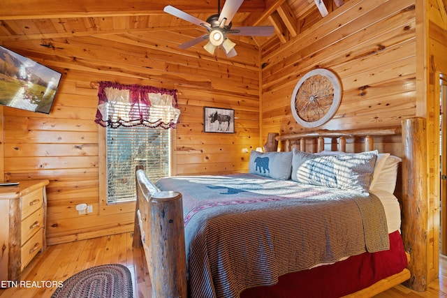 bedroom featuring vaulted ceiling with beams, wood walls, and light wood-type flooring