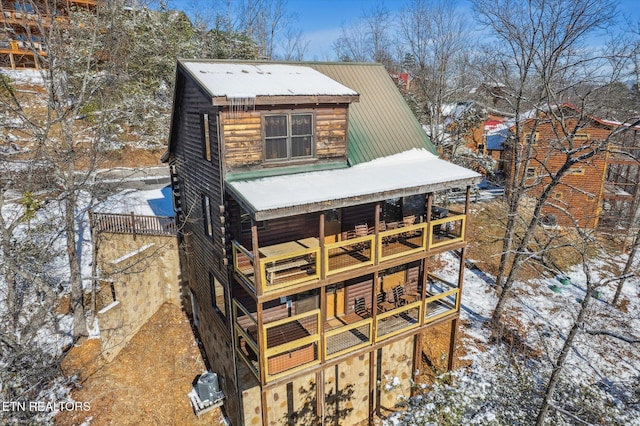 snow covered property with central AC unit and a balcony