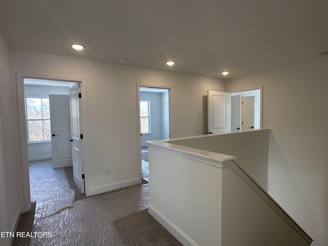 hall featuring dark colored carpet