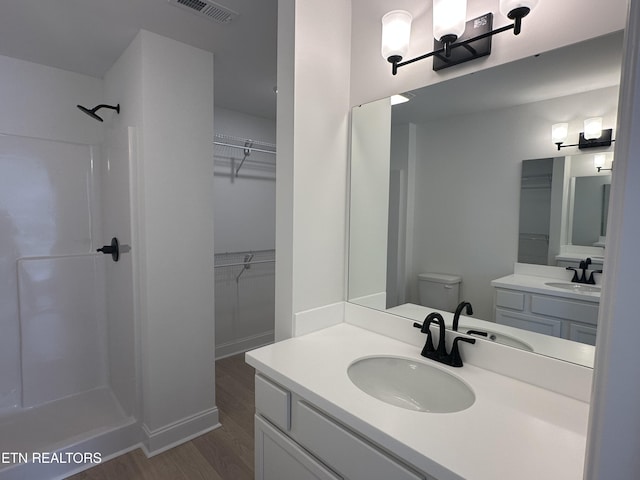 bathroom with wood-type flooring, toilet, vanity, and walk in shower