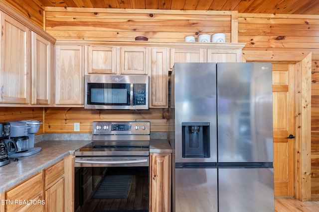 kitchen with appliances with stainless steel finishes, wooden walls, light brown cabinets, and wood ceiling