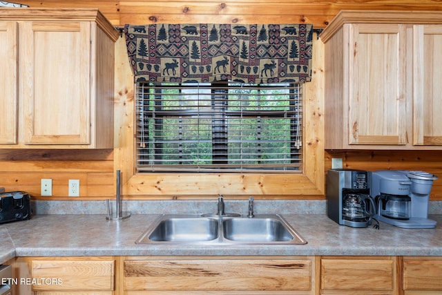 kitchen featuring wood walls, sink, and light brown cabinets