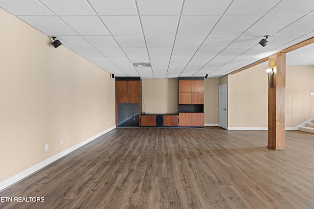 unfurnished living room with dark wood-type flooring and a paneled ceiling