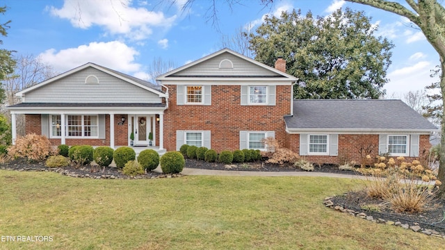 split level home featuring brick siding, a chimney, and a front lawn