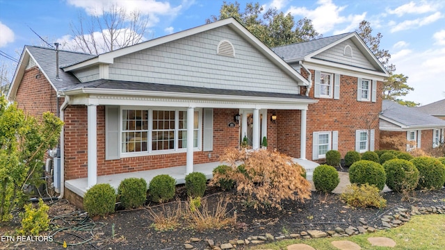 view of front of property with a shingled roof, a porch, and brick siding