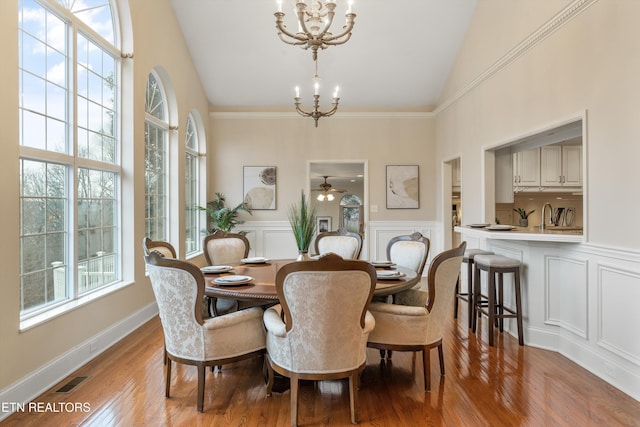 dining room with an inviting chandelier, light wood-style flooring, a decorative wall, and a wealth of natural light