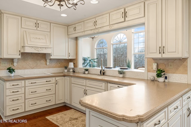 kitchen with dark wood-style floors, light countertops, cream cabinets, white electric cooktop, and a sink