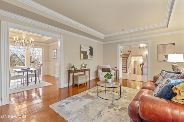 living room with crown molding, a tray ceiling, a chandelier, and hardwood / wood-style flooring