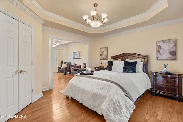 bedroom with baseboards, ornamental molding, a notable chandelier, and wood finished floors