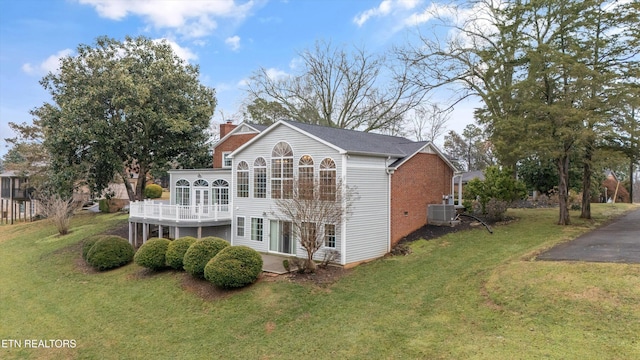 back of house featuring central air condition unit, a chimney, and a lawn