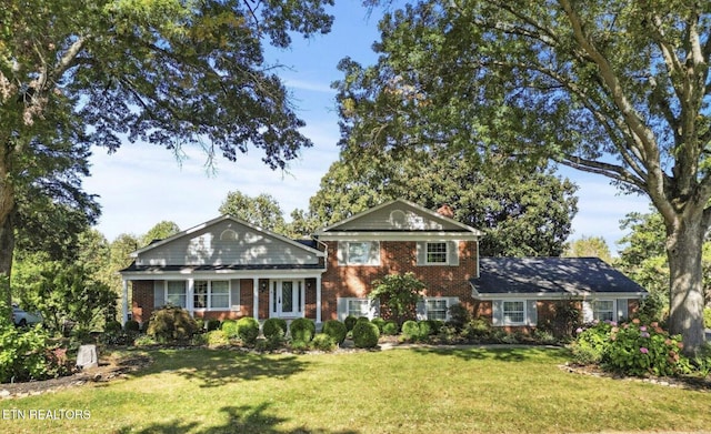 view of front facade with brick siding, a chimney, and a front lawn