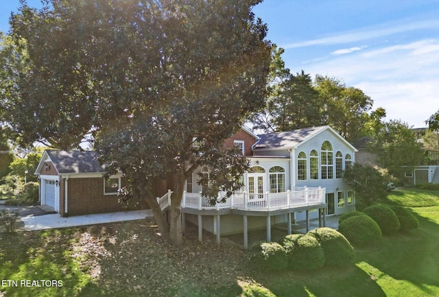 rear view of property with a garage, a deck, and brick siding