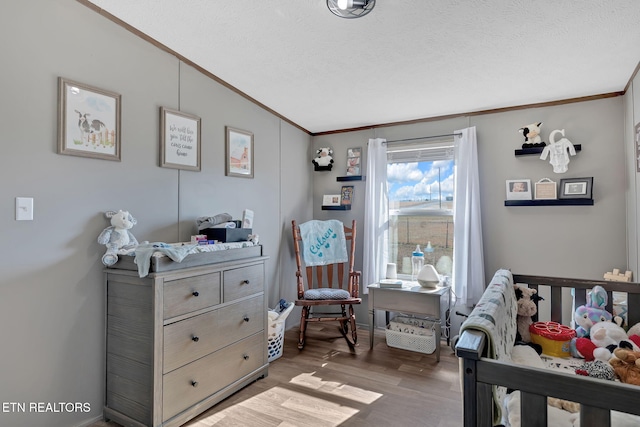 bedroom featuring hardwood / wood-style flooring, vaulted ceiling, ornamental molding, and a textured ceiling