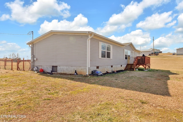 view of side of home with a wooden deck and a lawn