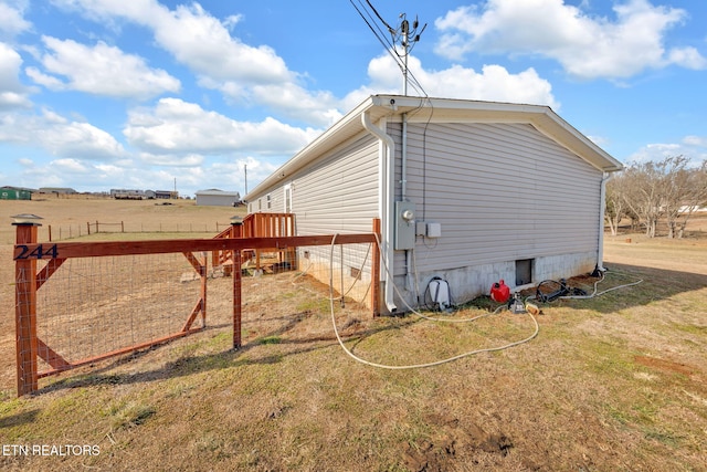 view of home's exterior with a rural view and a yard