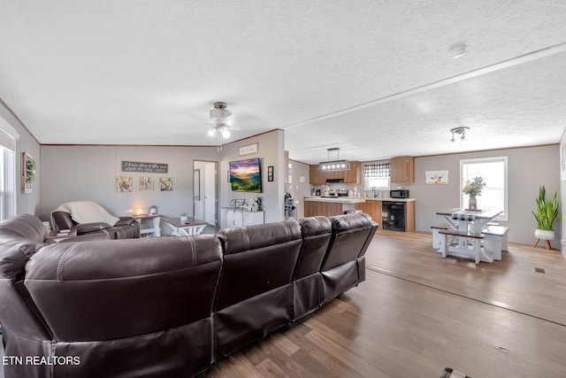 living room with wine cooler, ceiling fan, hardwood / wood-style flooring, and a textured ceiling