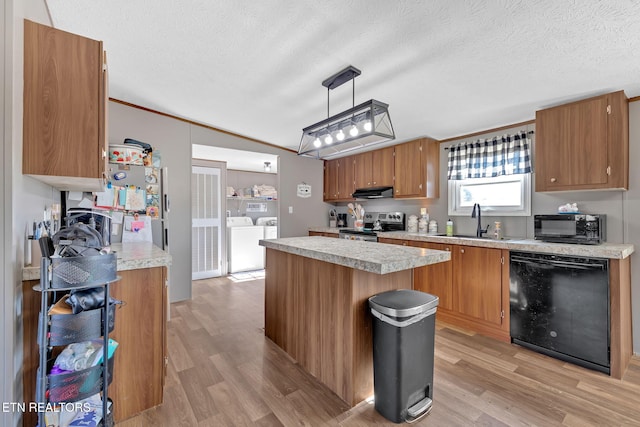 kitchen featuring pendant lighting, sink, washer and clothes dryer, a center island, and black appliances