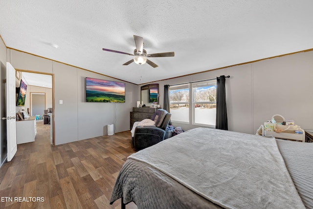 bedroom with crown molding, dark wood-type flooring, ceiling fan, a textured ceiling, and vaulted ceiling