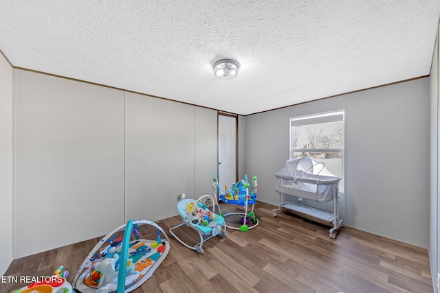 game room featuring crown molding, hardwood / wood-style floors, and a textured ceiling