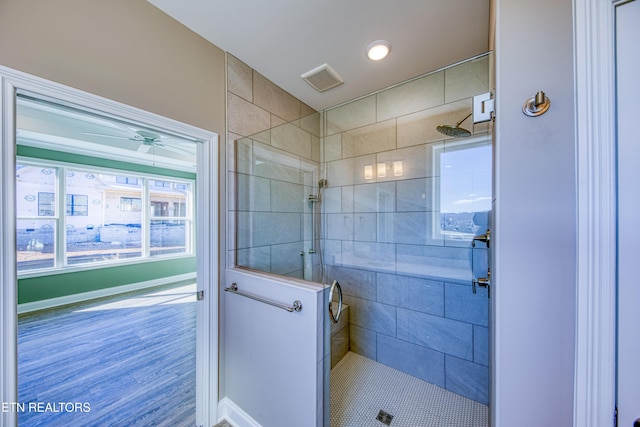 bathroom featuring a tile shower and ceiling fan