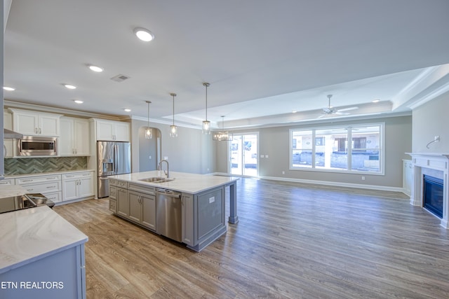 kitchen featuring sink, white cabinetry, stainless steel appliances, decorative light fixtures, and a raised ceiling