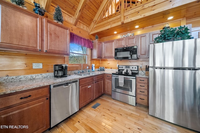 kitchen featuring vaulted ceiling with beams, wood ceiling, light stone counters, stainless steel appliances, and light wood-type flooring