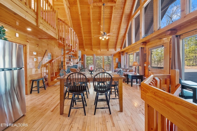 dining room with light wood-type flooring, a wealth of natural light, wood ceiling, and wooden walls