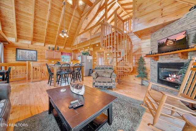 living room featuring wooden walls, wood ceiling, ceiling fan, and light hardwood / wood-style flooring