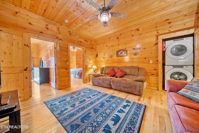 living room with ceiling fan, stacked washer / dryer, light wood-type flooring, and wooden ceiling