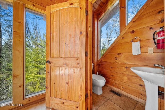 bathroom featuring toilet, sink, and wood walls