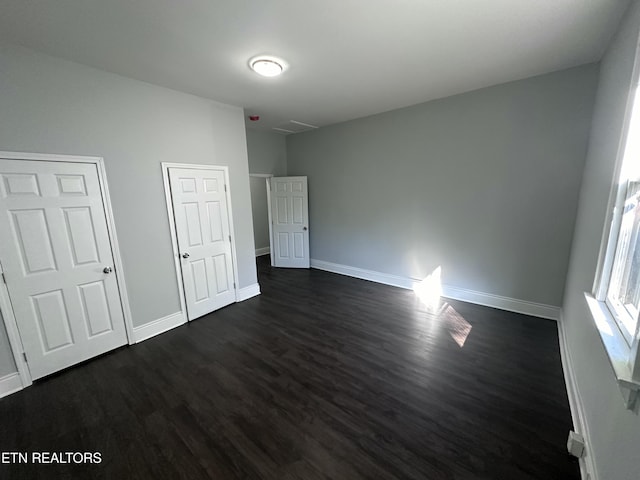 unfurnished bedroom with dark hardwood / wood-style flooring