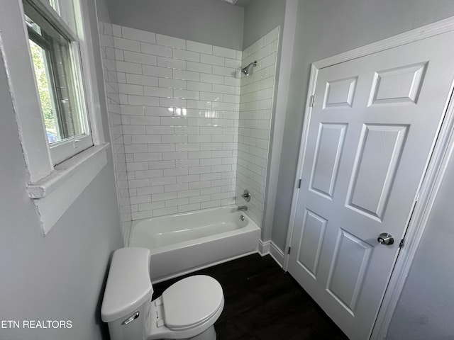 bathroom with hardwood / wood-style flooring, tiled shower / bath, and toilet