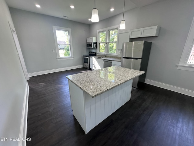 kitchen featuring white cabinetry, decorative light fixtures, a center island, appliances with stainless steel finishes, and plenty of natural light