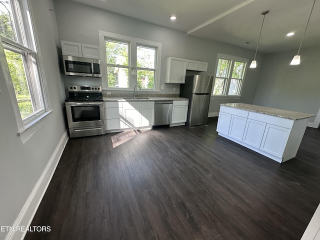 kitchen with hanging light fixtures, appliances with stainless steel finishes, and white cabinets