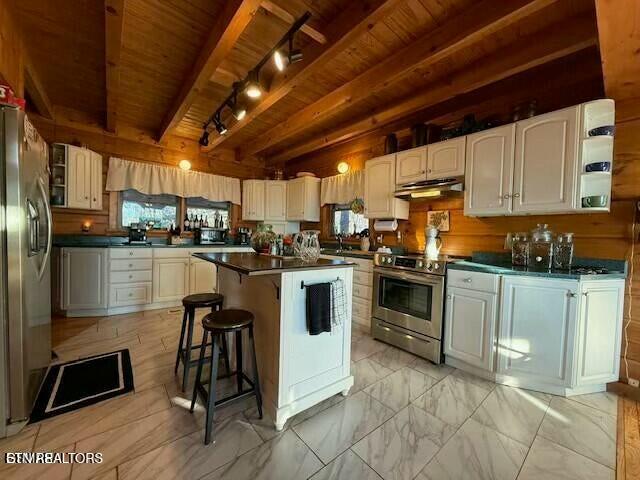 kitchen featuring beam ceiling, wood ceiling, a kitchen island, and appliances with stainless steel finishes