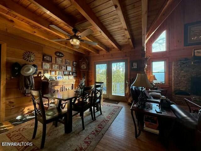 dining area with hardwood / wood-style floors, wooden walls, wooden ceiling, beam ceiling, and french doors