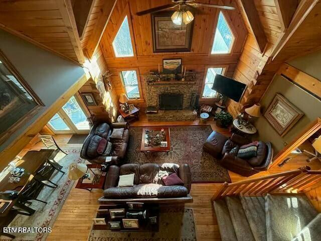 living room featuring a stone fireplace, plenty of natural light, hardwood / wood-style floors, and high vaulted ceiling