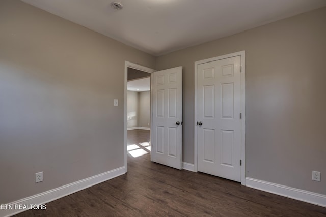 unfurnished bedroom with dark wood-type flooring