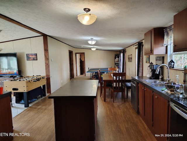 kitchen with a kitchen island, sink, stainless steel dishwasher, and light wood-type flooring