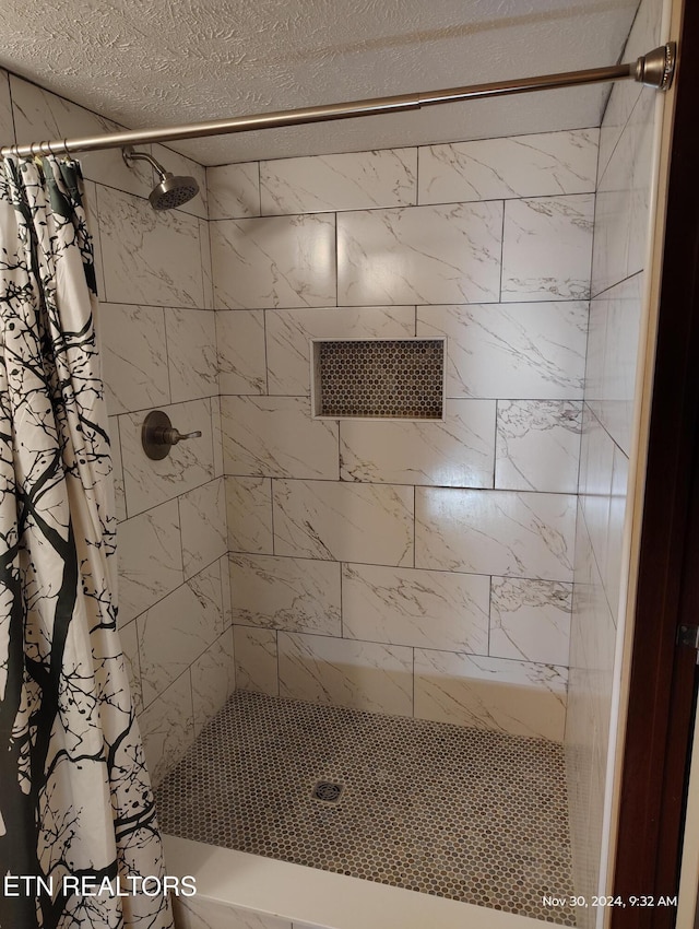 bathroom with curtained shower and a textured ceiling