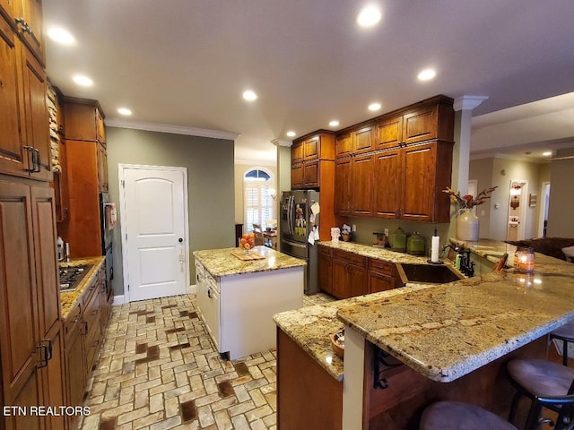 kitchen featuring a breakfast bar, sink, light stone counters, kitchen peninsula, and a kitchen island