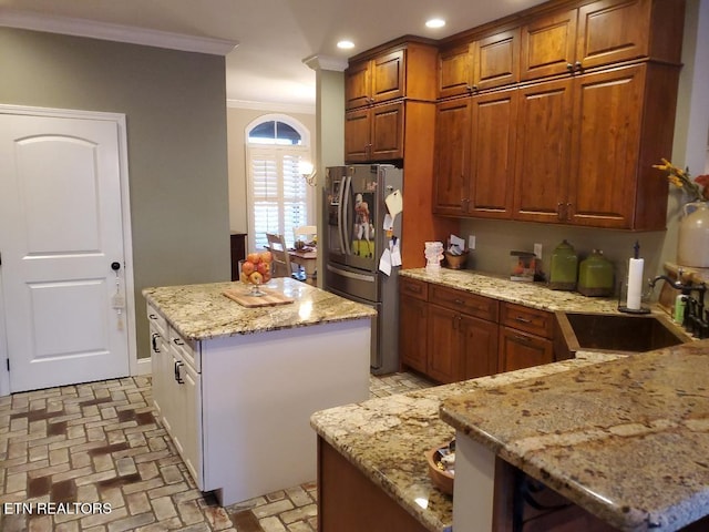 kitchen with light stone counters, sink, stainless steel fridge with ice dispenser, and a kitchen island