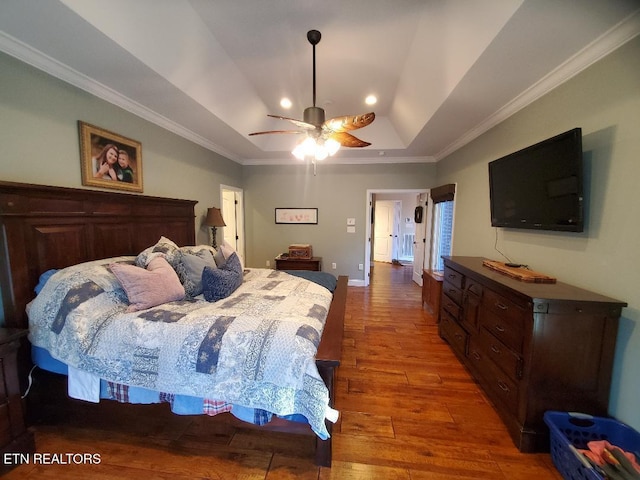 bedroom with hardwood / wood-style floors, ornamental molding, a raised ceiling, and ceiling fan