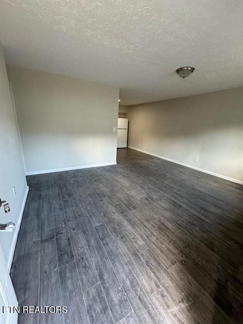 spare room featuring dark wood-type flooring and a textured ceiling