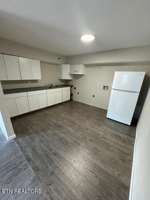 kitchen featuring sink, a textured ceiling, dark hardwood / wood-style floors, white fridge, and white cabinets