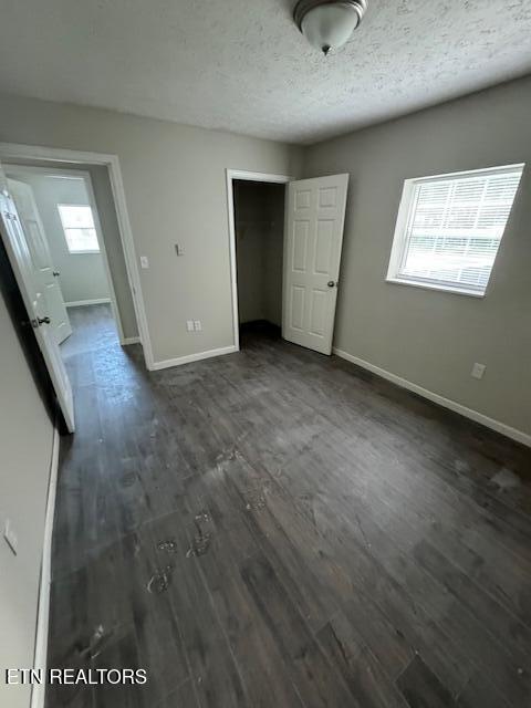 unfurnished bedroom featuring dark wood-type flooring, a closet, and a textured ceiling